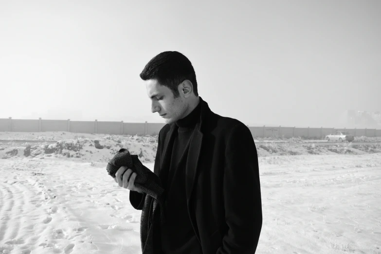 a man holding a bird standing in a snow covered field