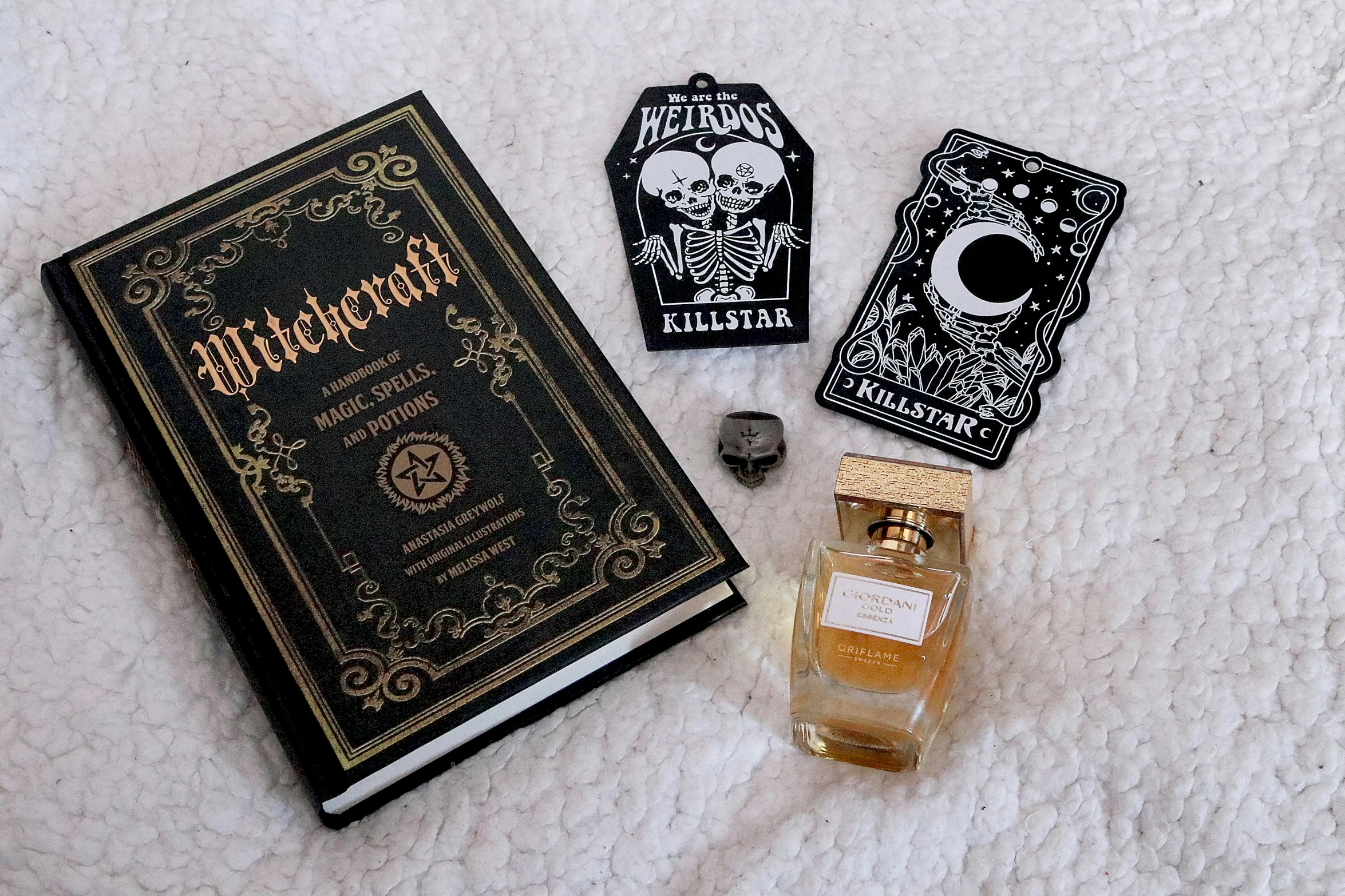 a book and perfume bottle laying on top of a blanket