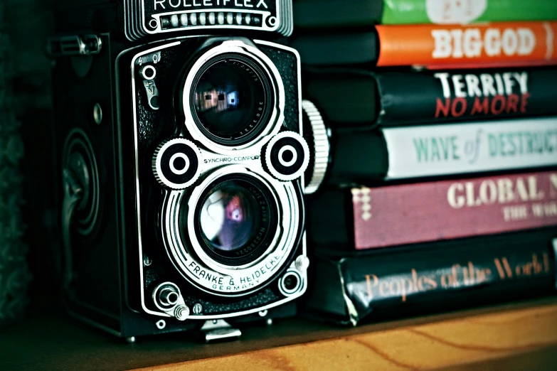 an old camera sitting next to books on a shelf