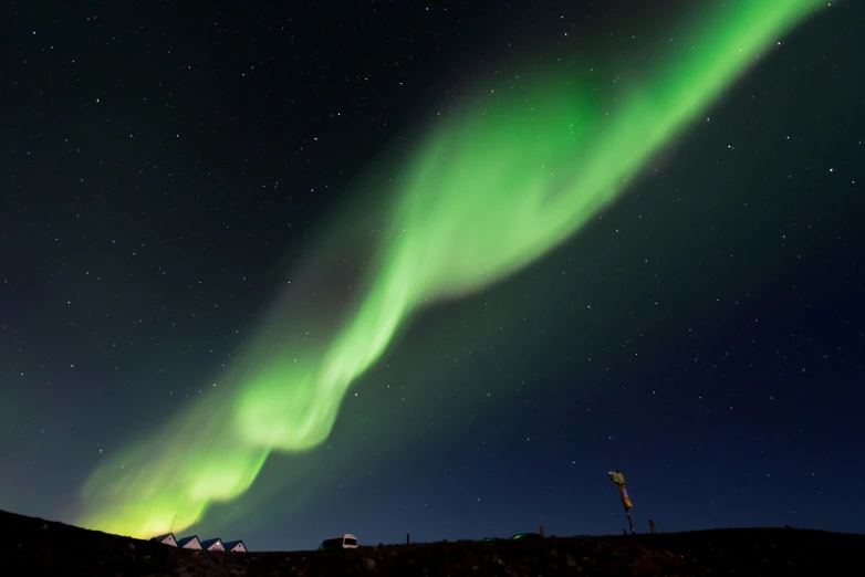 bright green light shines over a hill at night