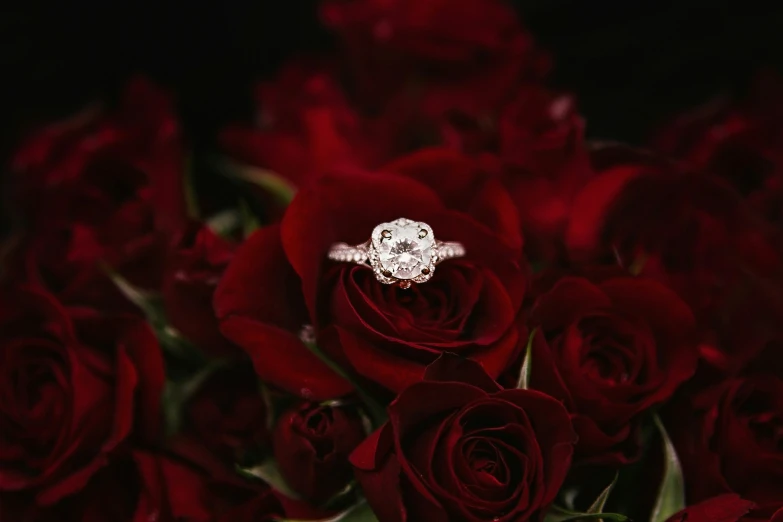 wedding ring laying on top of roses in a bouquet