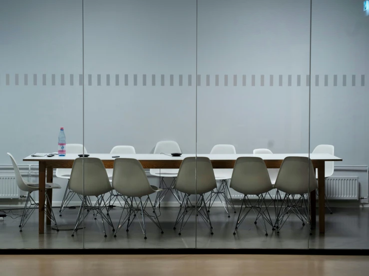 the table has eight chairs and is set up behind glass