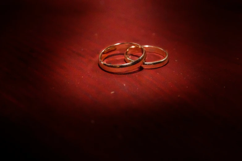 two wedding rings sitting on a table in red