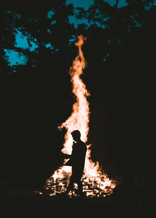 a silhouette of a person standing in front of a fire