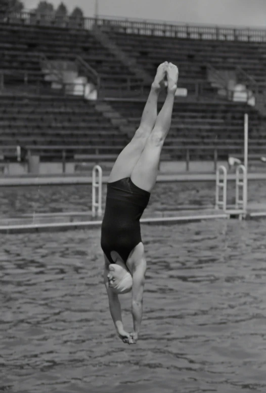 a man in a swimming suit doing a handstand on the diving board