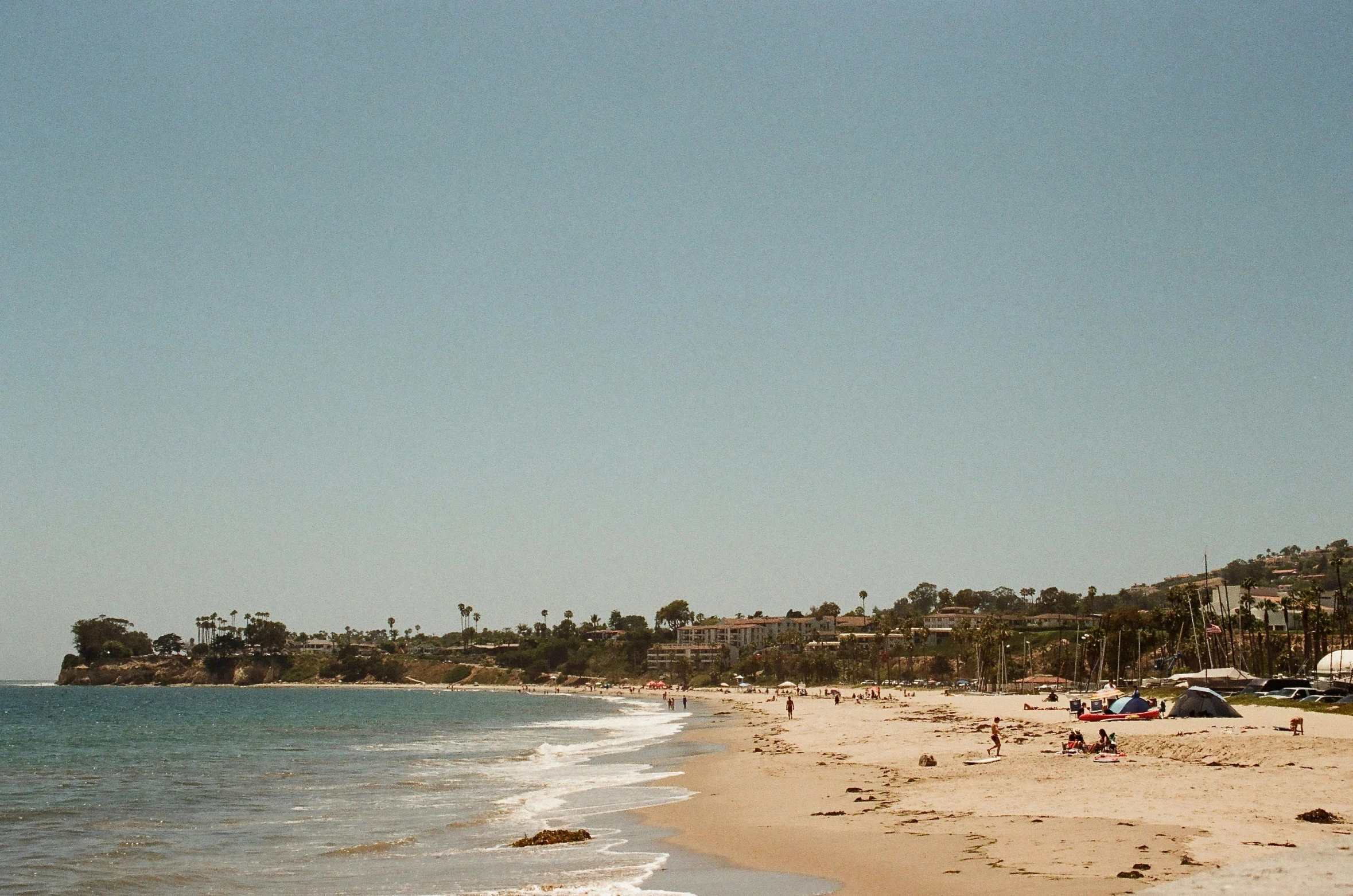 an empty beach and a city on the hill behind