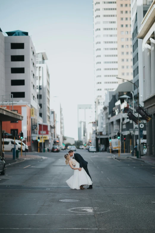 man and woman in formal wear kissing on the street