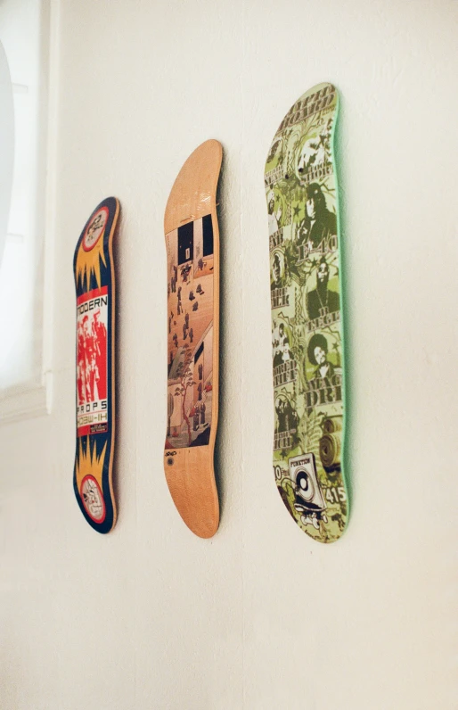 three skateboards laying on top of each other on a wall