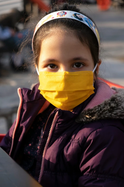 a girl with a yellow cloth mask on