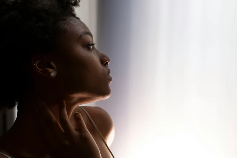 a woman looking out a window, wearing ear rings