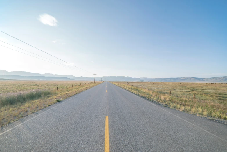 empty open road in desert with high power lines in the distance