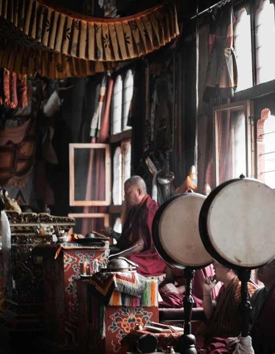 an old man sitting by a large drum in his living room