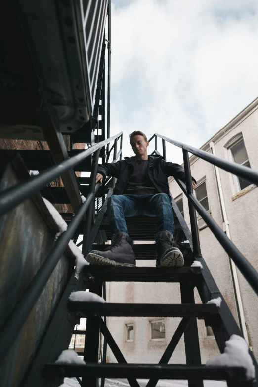 man sitting in the middle of stairs next to building