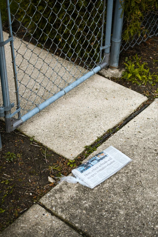 newspaper lying on the ground near a fence