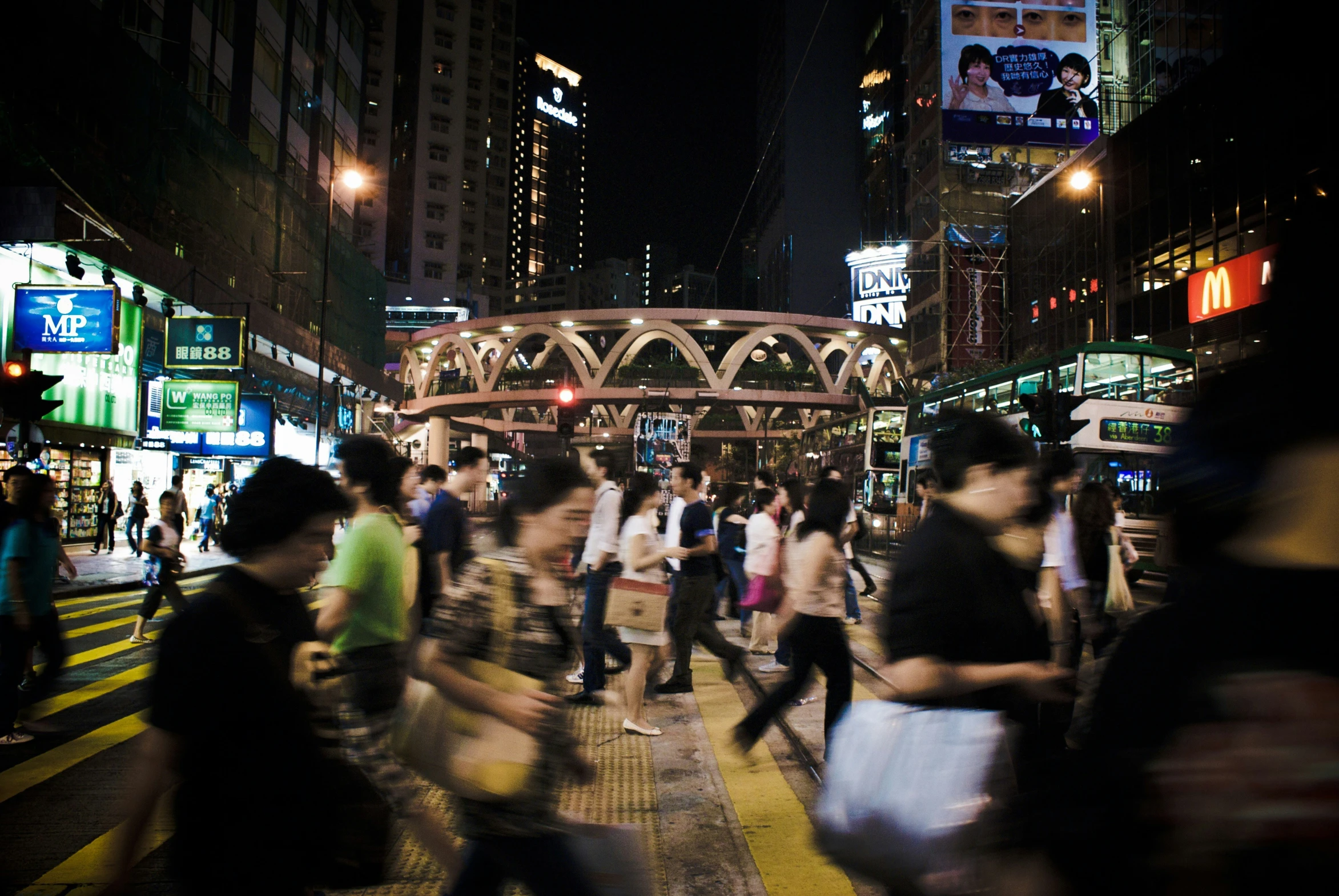 people walk along a busy street at night