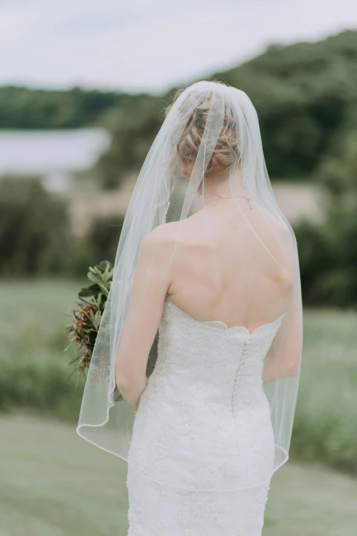 a bride in wedding dress walking toward a lake