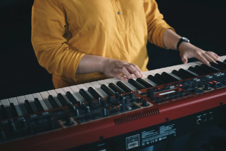 a person in yellow shirt playing music on electronic keyboard