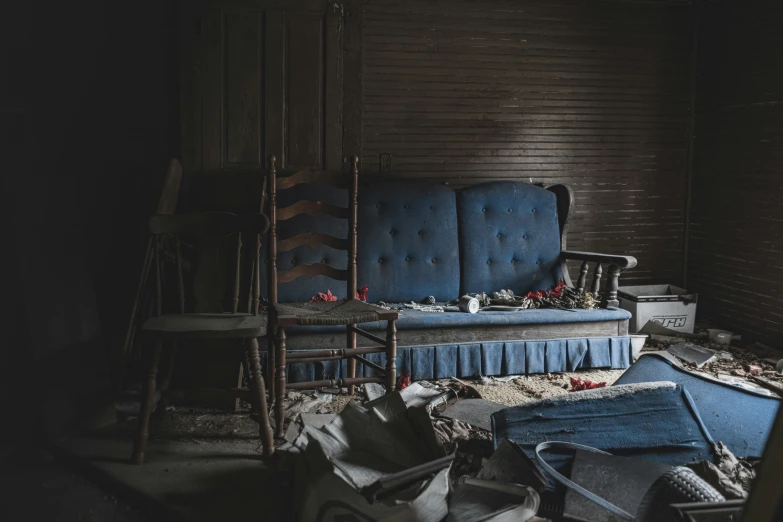 a dilapidated room with blue sofa and other objects scattered about