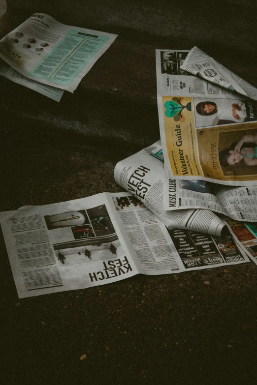 newspapers are spread on the floor with a black object behind it