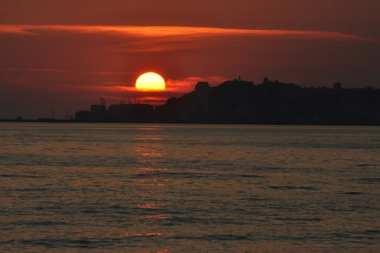 a red sun setting over a large body of water