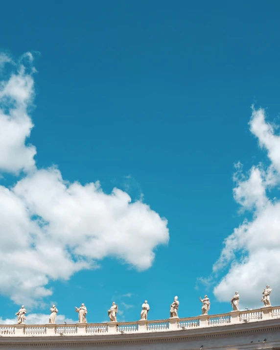 several statues on a roof top against a blue sky