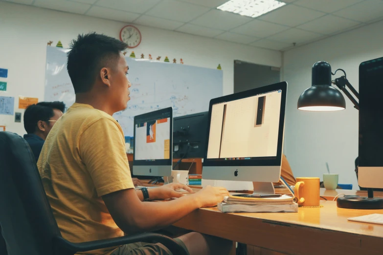 a man sitting in front of two computer monitors