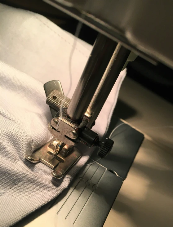 close up s of sewing machine with white cloth