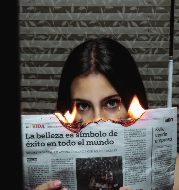 a woman reading a newspaper with flames on it