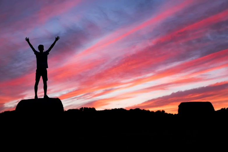 a person on a hill holding their hands up in the air