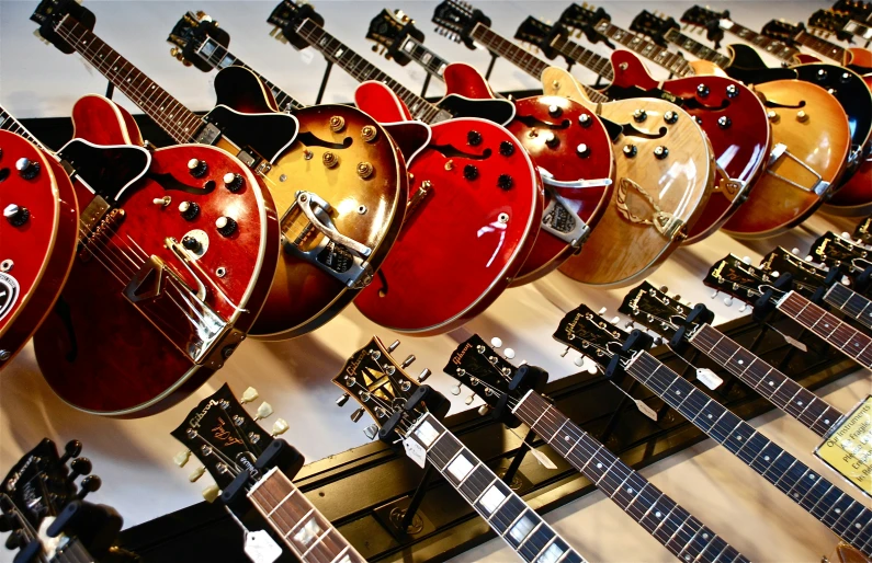 several guitars sitting side by side against a wall