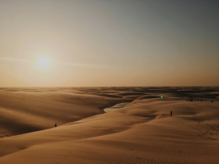 the sun rises in the distance over dunes in death valley national park