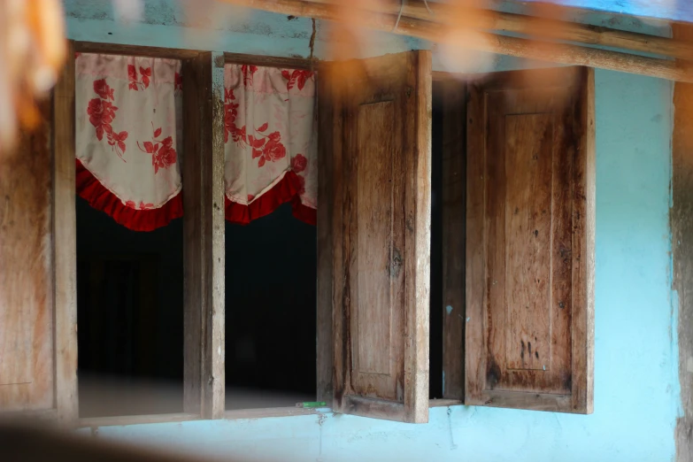 three open wooden windows in a blue house