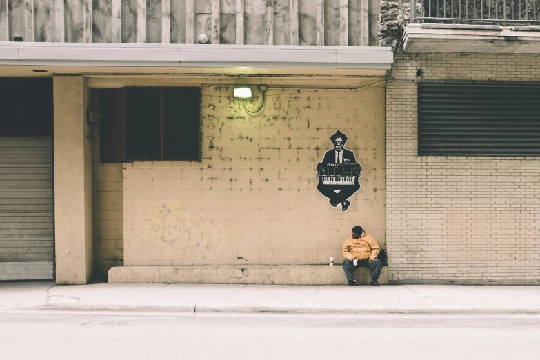 a person sitting against the side of a building