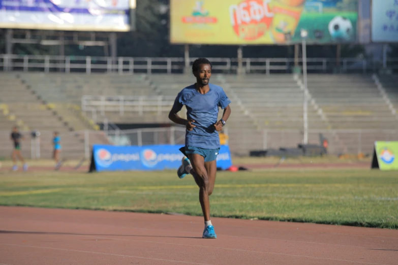 a man in blue shirt and shorts running down a race track