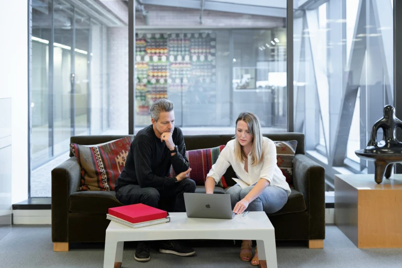 man and woman sitting on brown couch near glass wall