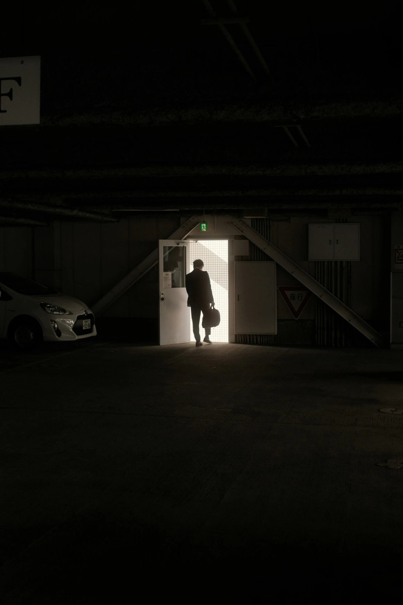 person walking through the door of a parking garage in a dark area