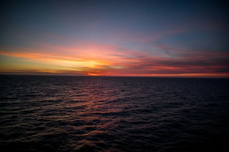 the sunset behind the clouds is reflected on the water