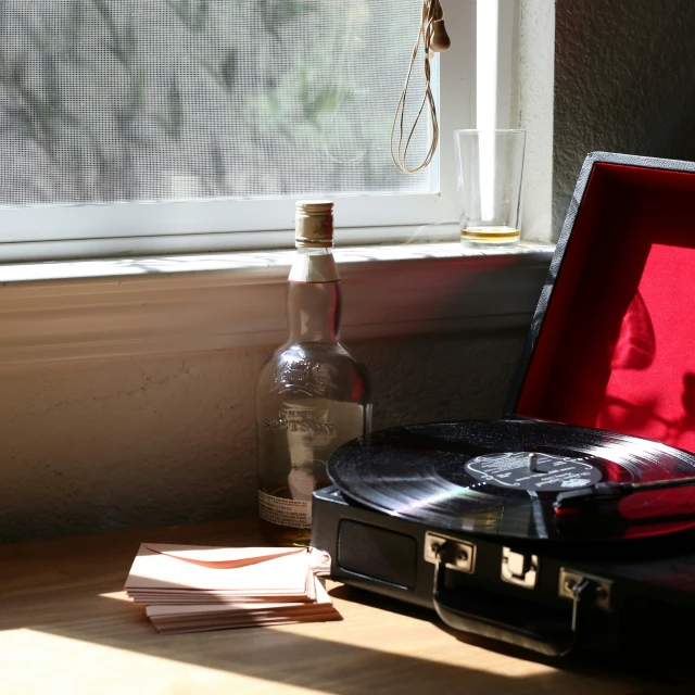 a record player with a box, bottle and papers on a table