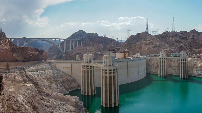 a large dam near mountains and a bridge