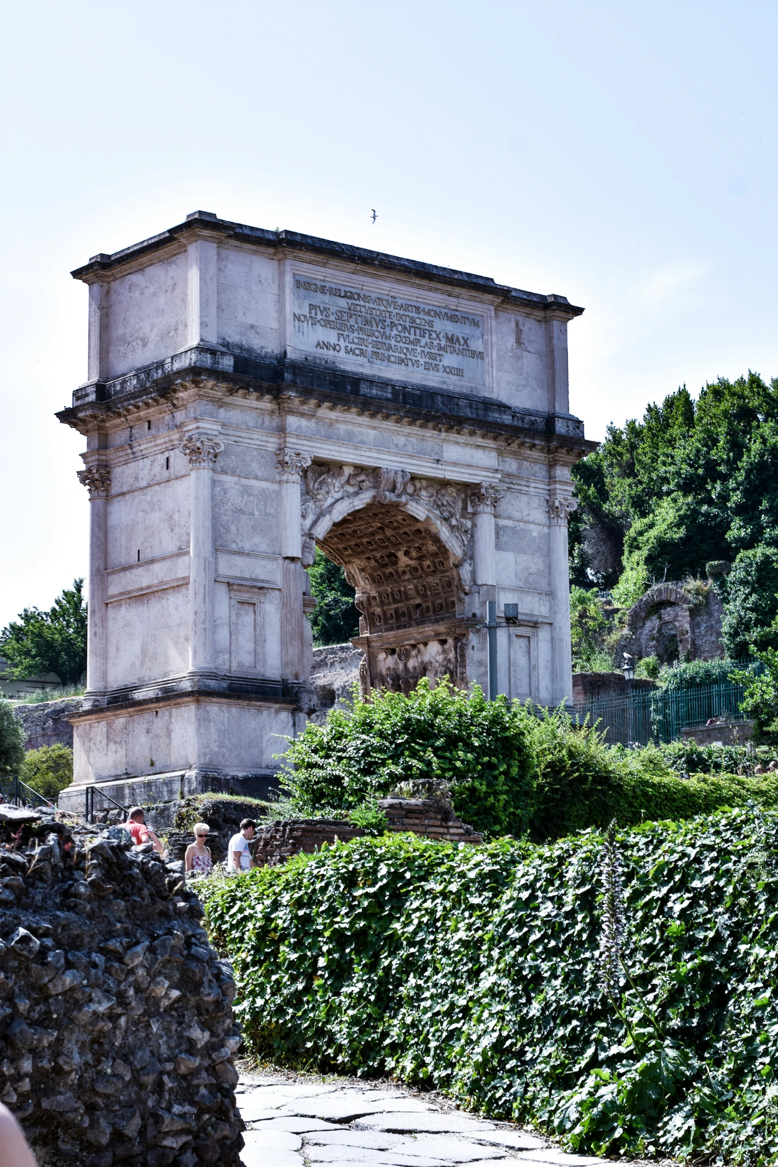 a stone structure near many plants on the side of a hill