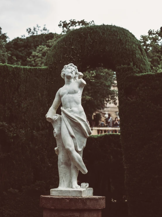 an old statue of a man surrounded by trimmed hedges