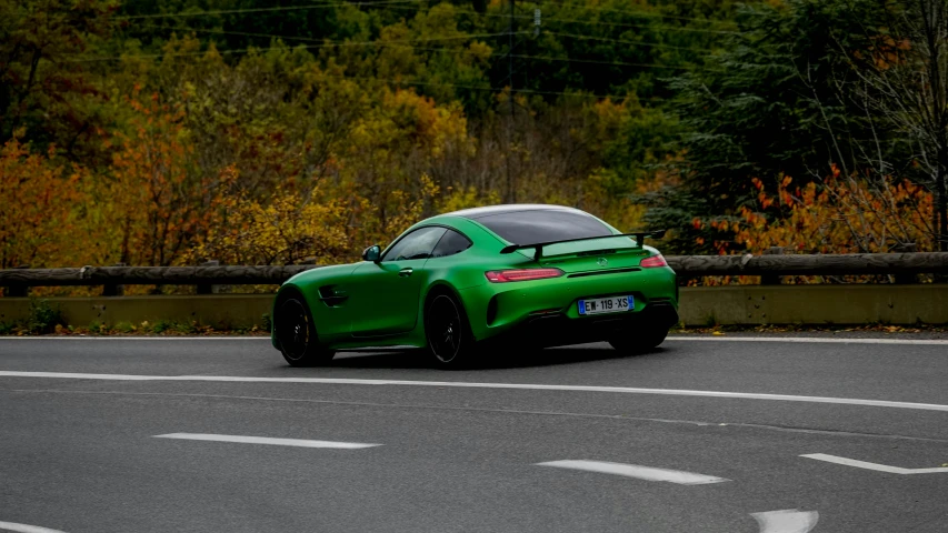 the green sports car is driving on a road