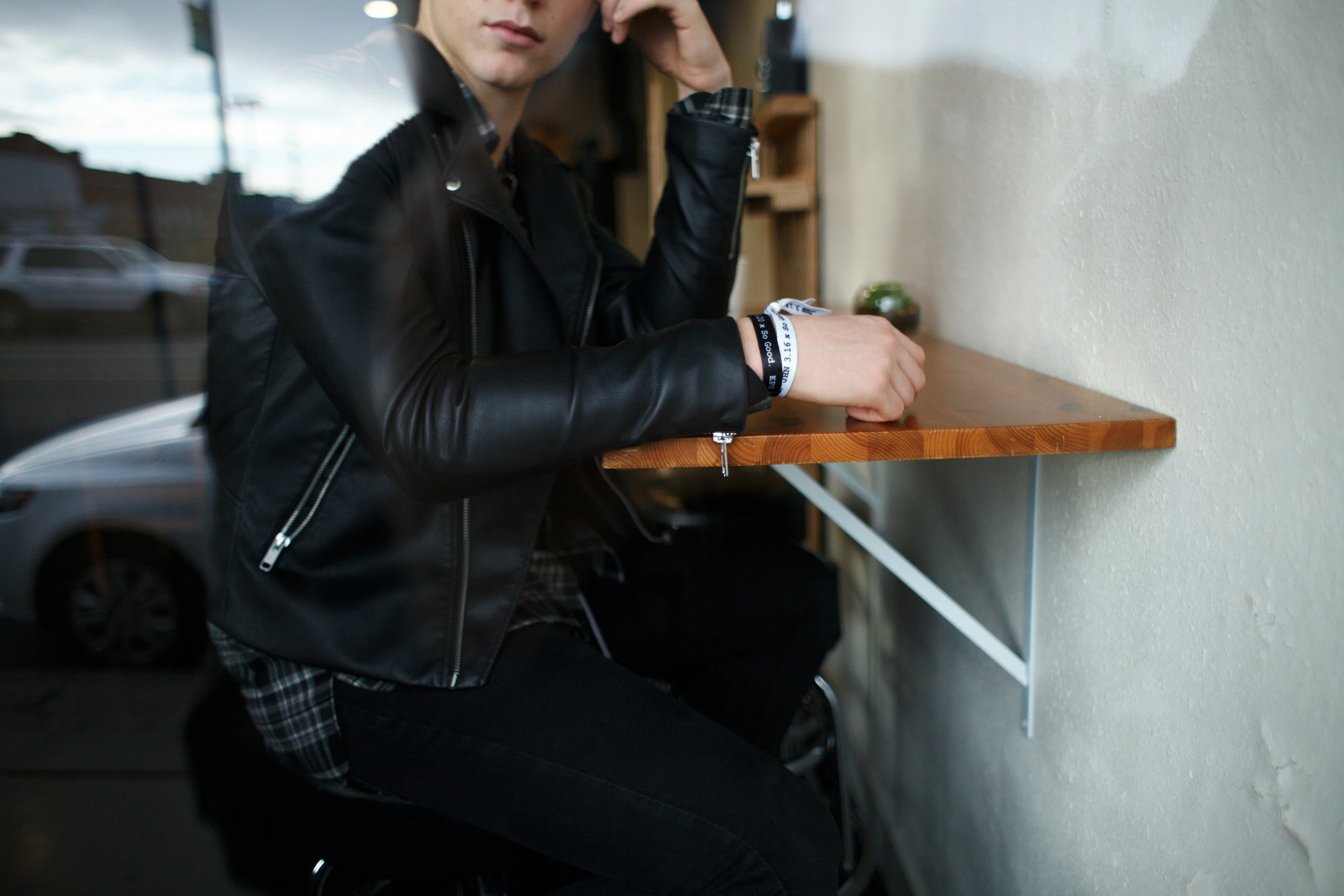 a man with a black jacket sitting at a wooden table