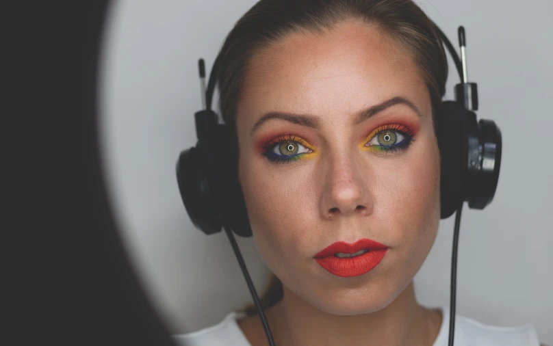 woman with red lipstick, headphones and makeup looking at camera