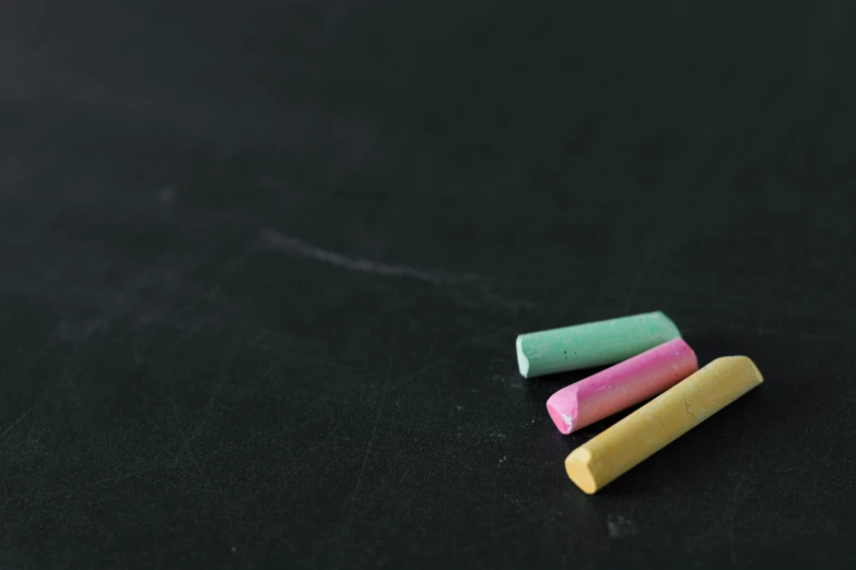 three crayons in pastel colors on black cloth