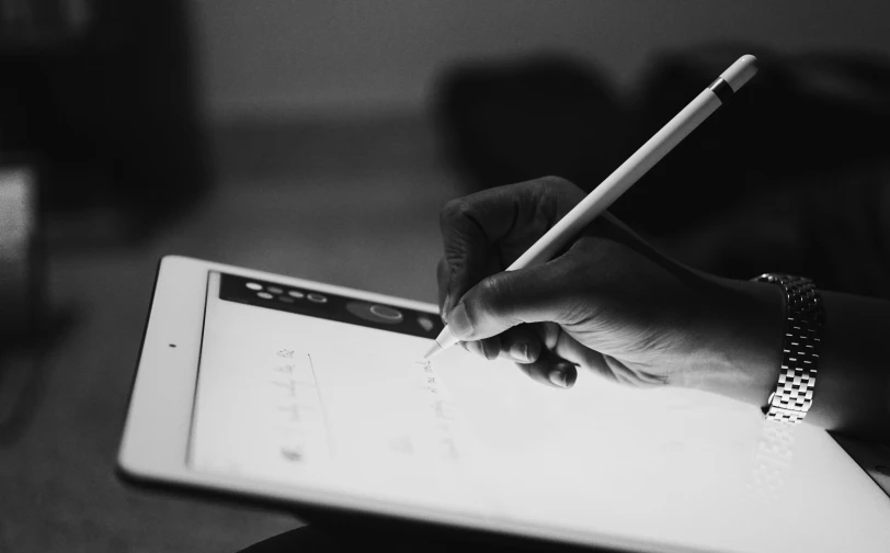 a woman with a pencil in her hand writes on a sheet of paper while holding a laptop computer