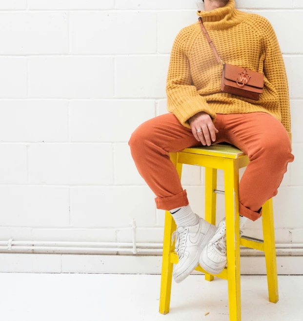 a young woman sits on a yellow stool