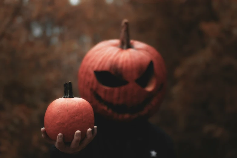 a child wearing a jack - o'- lantern costume, holding an apple