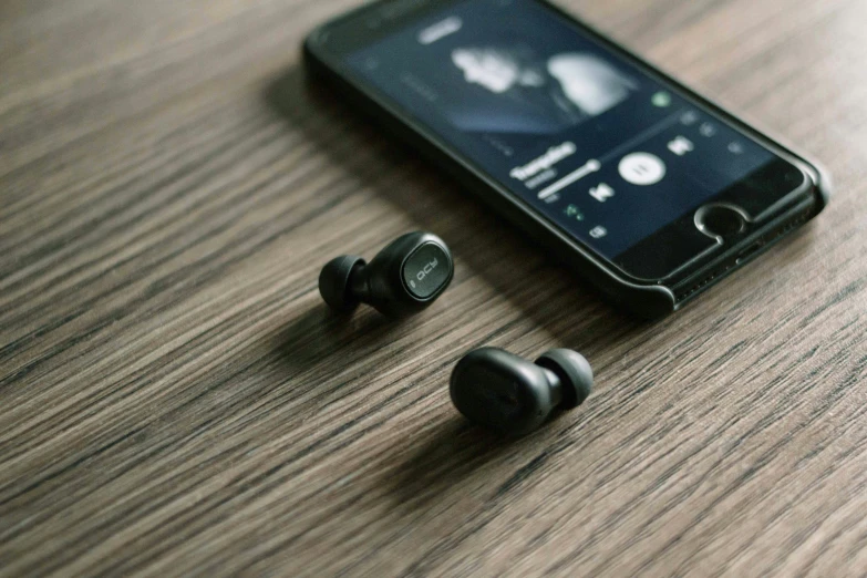 an old black phone on top of a table next to a pair of earbuds