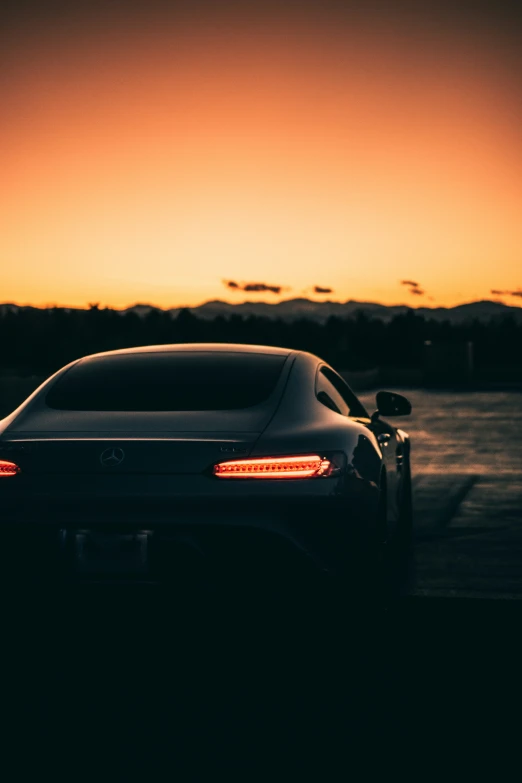 a sports car is seen against a sunset